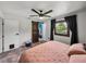 A bedroom with ceiling fan, a pink quilt and a barn door leading to a colorful room at 7150 Orange Way, Lakeland, FL 33810
