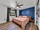 Bedroom featuring a king bed, modern lighting, wood flooring, and a blue accent wall at 7150 Orange Way, Lakeland, FL 33810