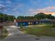Evening shot of a blue single-story house featuring a paved driveway and a neatly manicured lawn at 7150 Orange Way, Lakeland, FL 33810