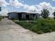 View of exterior of the home with driveway and overgrown lawn at 745 Drawdy Rd, Babson Park, FL 33827