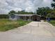 Exterior shot of property showing the house, overgrown yard, and driveway at 745 Drawdy Rd, Babson Park, FL 33827