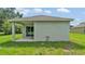 Back exterior of the house showing the outdoor patio area with a sliding glass door and backyard lawn at 1025 Lakewood Ct, Lakeland, FL 33801