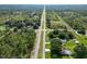 Aerial view showcases the tranquil setting of homes nestled among lush greenery and a long rural road at 2700 Park Ave, Indian Lake Estates, FL 33855