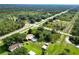 Aerial shot showcases the home with a pool, surrounded by a verdant landscape with a quiet road nearby at 2700 Park Ave, Indian Lake Estates, FL 33855
