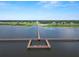 Expansive view of a pier extending into a serene lake, framed by lush greenery on the shore at 2700 Park Ave, Indian Lake Estates, FL 33855