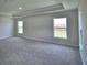 Bright bedroom with plush carpeting, tray ceiling, and large windows overlooking the lawn at 5427 Waterside Dr, Auburndale, FL 33823
