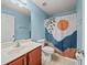 Bright bathroom with blue walls, decorative shower curtain, and a wood vanity at 5611 Aral Dr, Lakeland, FL 33805