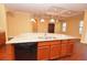 Large kitchen island shows chrome faucet, black dishwasher, natural-wood cabinets, granite countertops, and pendant lights at 6408 Christina Chase Pl, Lakeland, FL 33813
