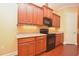 The kitchen features natural-wood cabinets, granite countertops, under cabinet lighting, and black appliances at 6408 Christina Chase Pl, Lakeland, FL 33813