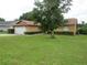 A single-story house featuring a green lawn, mature tree, and neatly trimmed hedges enhance curb appeal at 7923 Glenridge E Loop, Lakeland, FL 33809