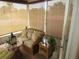 The screened porch has wood furniture with comfortable cushioning and a view of the greenery outside at 7923 Glenridge E Loop, Lakeland, FL 33809