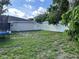 Backyard showcasing a grassy area, surrounded by a white fence and mature trees at 105 Byron Pl, Winter Haven, FL 33884
