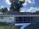 Backyard showcasing a screened porch with a hammock, grassy area, surrounded by mature trees at 105 Byron Pl, Winter Haven, FL 33884
