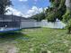 Backyard featuring a trampoline, grassy area, surrounded by a white fence and mature trees at 105 Byron Pl, Winter Haven, FL 33884