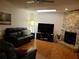 Cozy living room with a stone fireplace, ceiling fan, wood floors, and comfortable leather seating at 1470 Ne Old Mill Dr, Deltona, FL 32725
