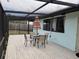 Covered screened patio featuring a table and chairs, perfect for outdoor enjoyment and entertaining at 1470 Ne Old Mill Dr, Deltona, FL 32725