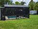 Backyard featuring a screened in pool with outdoor seating, grass, and a trailer in the background at 806 South St, New Smyrna Beach, Fl 32168, FL 32168
