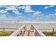 Wooden walkway leading to a beautiful beach with soft sand and gentle waves, perfect for a day of relaxation at 4303 Sea Mist Dr # 225, New Smyrna Beach, FL 32169