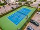 Aerial view of a community tennis court in a landscaped area with parking, offering recreational opportunities for residents at 1 Riverwalk Dr # 202, New Smyrna Beach, FL 32169