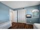 Comfortable bedroom with blue walls, wood floors, closet, beds, and wall-mounted television at 3663 S Atlantic Ave # 21C, New Smyrna Beach, FL 32169