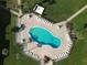 Aerial view of a kidney-shaped community pool, featuring tables, lounge chairs, and landscaping within a fenced-in patio at 3663 S Atlantic Ave # 21C, New Smyrna Beach, FL 32169