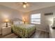 Comfortable bedroom featuring a queen bed, ceiling fan, and a bright window with outside views at 3180 Ocean Shore Blvd # 208, Ormond Beach, FL 32176