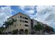 Multi-story building with neutral colors, balconies, palm trees, and parking spaces in front on a beautiful sunny day at 424 Luna Bella Ln # 433, New Smyrna Beach, FL 32168