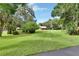 Expansive backyard featuring a well-manicured lawn, mature trees, and a charming home with a screened patio at 2536 Paige Ave, New Smyrna Beach, FL 32168