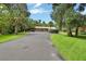 Long paved driveway leading to a three-car garage and carport, surrounded by lush greenery and mature trees at 2536 Paige Ave, New Smyrna Beach, FL 32168