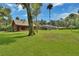 Sprawling lawn with log cabin home and screened-in pool area under a sunny, blue sky at 2536 Paige Ave, New Smyrna Beach, FL 32168