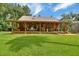 Charming log cabin home featuring a spacious porch with outdoor seating, surrounded by lush greenery and a manicured lawn at 2536 Paige Ave, New Smyrna Beach, FL 32168