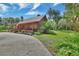 Rustic log cabin with an inviting porch, lush greenery, and a spacious driveway at 2536 Paige Ave, New Smyrna Beach, FL 32168