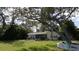 Charming single-story home with a screened lanai, grill, and a kayak resting under a shady tree at 1949 Bayview Dr, New Smyrna Beach, FL 32168