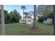 Spacious yard with mature trees, outbuilding, and golf cart parked near the yellow house at 1949 Bayview Dr, New Smyrna Beach, FL 32168