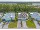 An aerial view showcases three houses with well-manicured lawns and driveways in a lush, green neighborhood at 306 Coral Reef Way, Daytona Beach, FL 32124