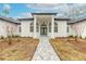 Front entrance with gray stone walkway leading to a white house with arched entryway at 1371 Melonie Trl, New Smyrna Beach, FL 32168