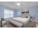 A primary bedroom featuring blue walls, a ceiling fan, and a large window for natural light at 1768 Creekwater Blvd, Port Orange, FL 32128