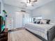 Comfortable bedroom with a ceiling fan, white dresser, closet, and light blue accent wall at 701 N Atlantic Ave # 202, New Smyrna Beach, FL 32169