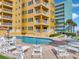 Exterior building view of a pool deck with chairs and manicured lawn at 701 N Atlantic Ave # 202, New Smyrna Beach, FL 32169