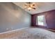 Bedroom with carpet flooring, gray and purple accent walls, a ceiling fan, and ample natural light at 1277 Harms Way, Port Orange, FL 32129