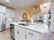 Kitchen island features a sink, white cabinets, stainless steel appliances, and wood-look flooring at 452 Lime Ave, Daytona Beach, FL 32124