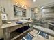 Stylish bathroom with stone tile shower, wood-look vanity, decorative mirror, and unique tile floors at 501 N Causeway # 2050, New Smyrna Beach, FL 32169