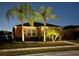 Charming single-story home with lush landscaping and two swaying palm trees in the front yard, all beautifully lit at night at 3325 Pintello Ave, New Smyrna Beach, FL 32168