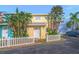 Charming yellow two-story home with a white picket fence and lush tropical landscaping at 4017 Saxon Dr, New Smyrna Beach, FL 32169