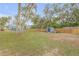 Lush green backyard with a wooden fence, mature trees, and a small storage shed enhance the property's appeal at 532 Faulkner St, New Smyrna Beach, FL 32168