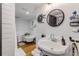 Bathroom with white sink and walls, round mirror, hardwood floors, tub, and unique decorative sun at 532 Faulkner St, New Smyrna Beach, FL 32168