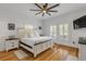 Bright bedroom featuring white walls, hardwood floors, ceiling fan, and natural light from the large windows at 532 Faulkner St, New Smyrna Beach, FL 32168