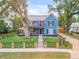 Charming two-story blue house with a metal roof, front porch, balcony, landscaped yard, and decorative fencing at 532 Faulkner St, New Smyrna Beach, FL 32168