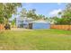 Backyard featuring a detached garage, lush green grass, and wooden fencing surrounding the charming two-story blue home at 532 Faulkner St, New Smyrna Beach, FL 32168