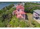 An aerial view highlighting the lush landscaping, unique architecture, and serene setting of a pink-colored home at 824 Garfish Ave, New Smyrna Beach, FL 32169